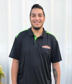 Male SERVPRO employee wearing a black polo standing in front of a white wall